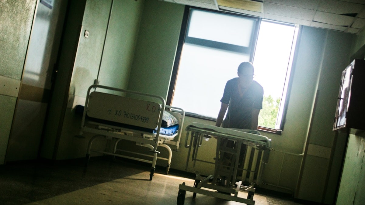 Person sitting by a window in an empty hospital room